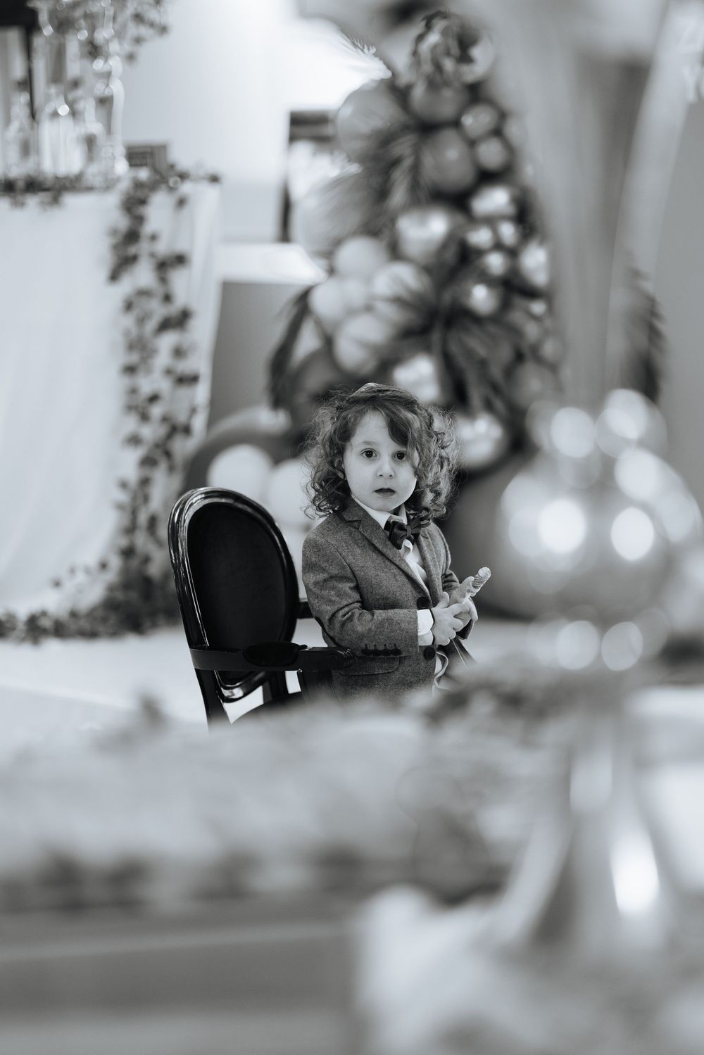 A black and white artistic photo of a dining room interior with holiday decor and bokeh lights in soft focus.