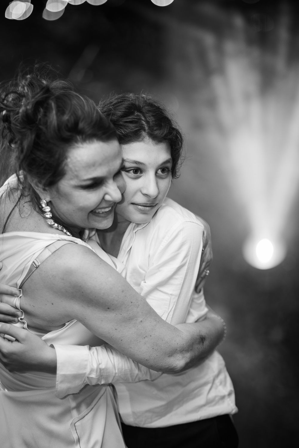 A tender black and white moment captured of two people embracing and smiling at a special event.