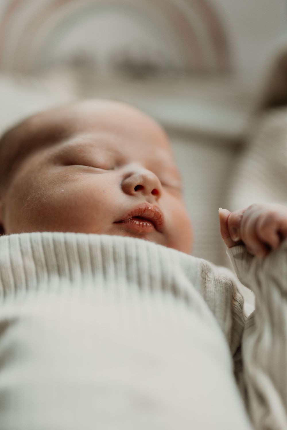 Close-up details of sleeping baby's face partially covered in white knit fabric.