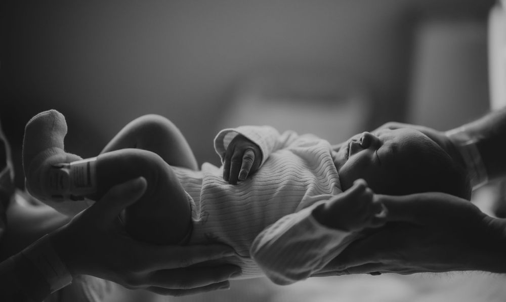 Black and white image of a sleeping newborn baby in soft lighting.