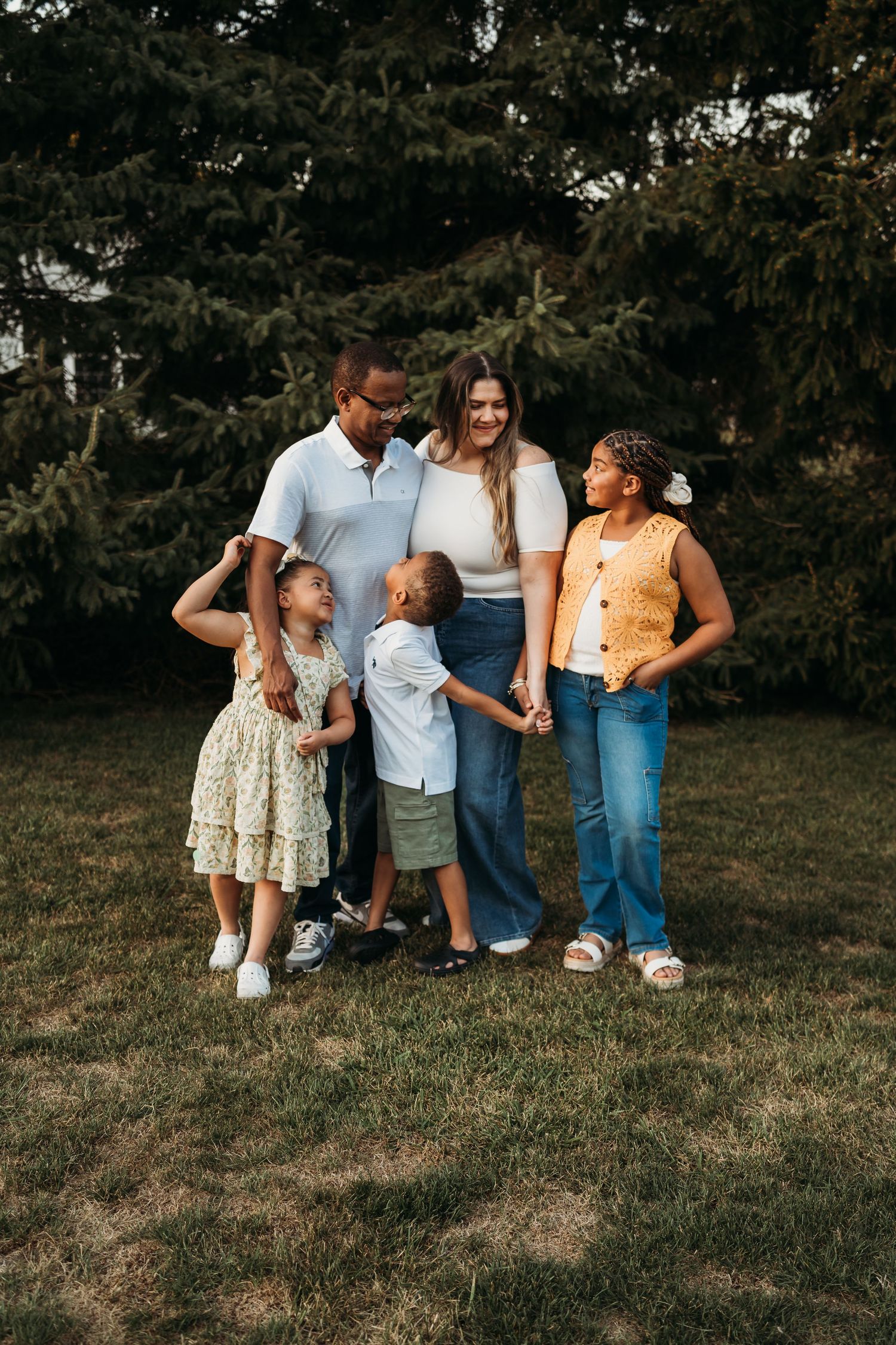 Family members walking together on grass during golden hour outdoor photo session.