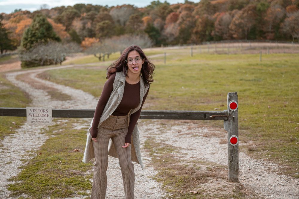 Someone enjoying a sunny autumn day on a dirt path with fall foliage and trail markers in the background.