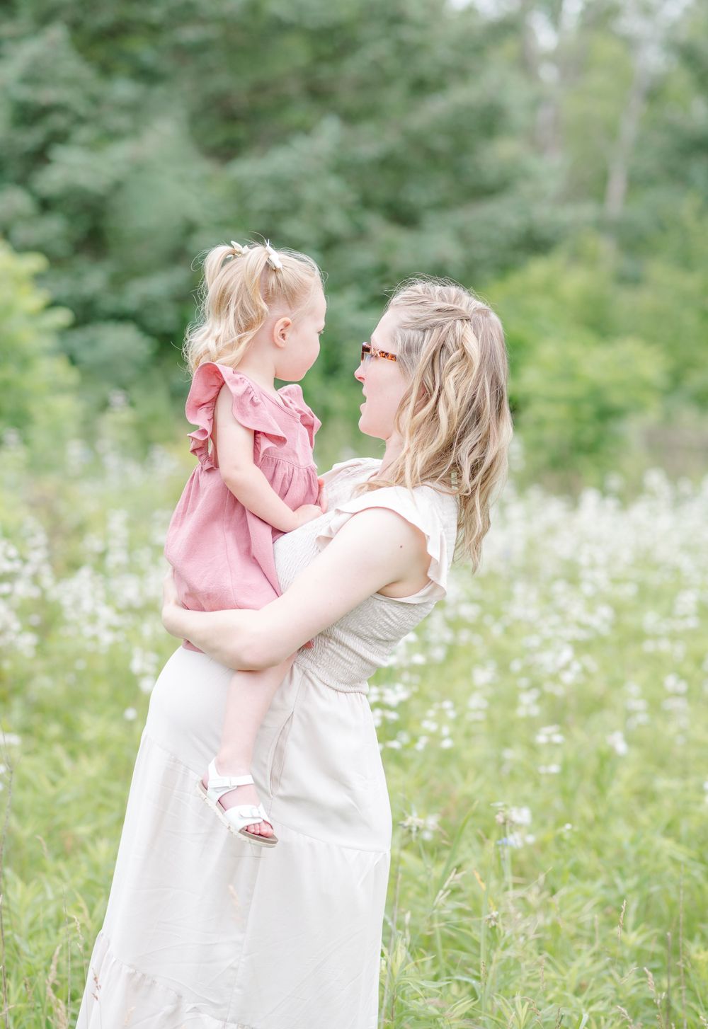 Expecting mother holding toddler in pink dress during outdoor maternity session in Normal, Illinois by Julie Loy Photography