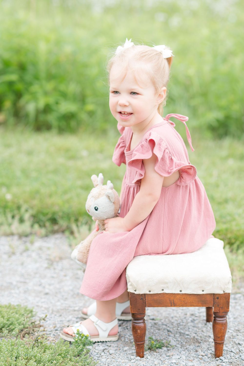 Toddler sitting on a bench wearing a pink dress during an outdoor family photography session in Normal, Illinois by Julie Loy Photography