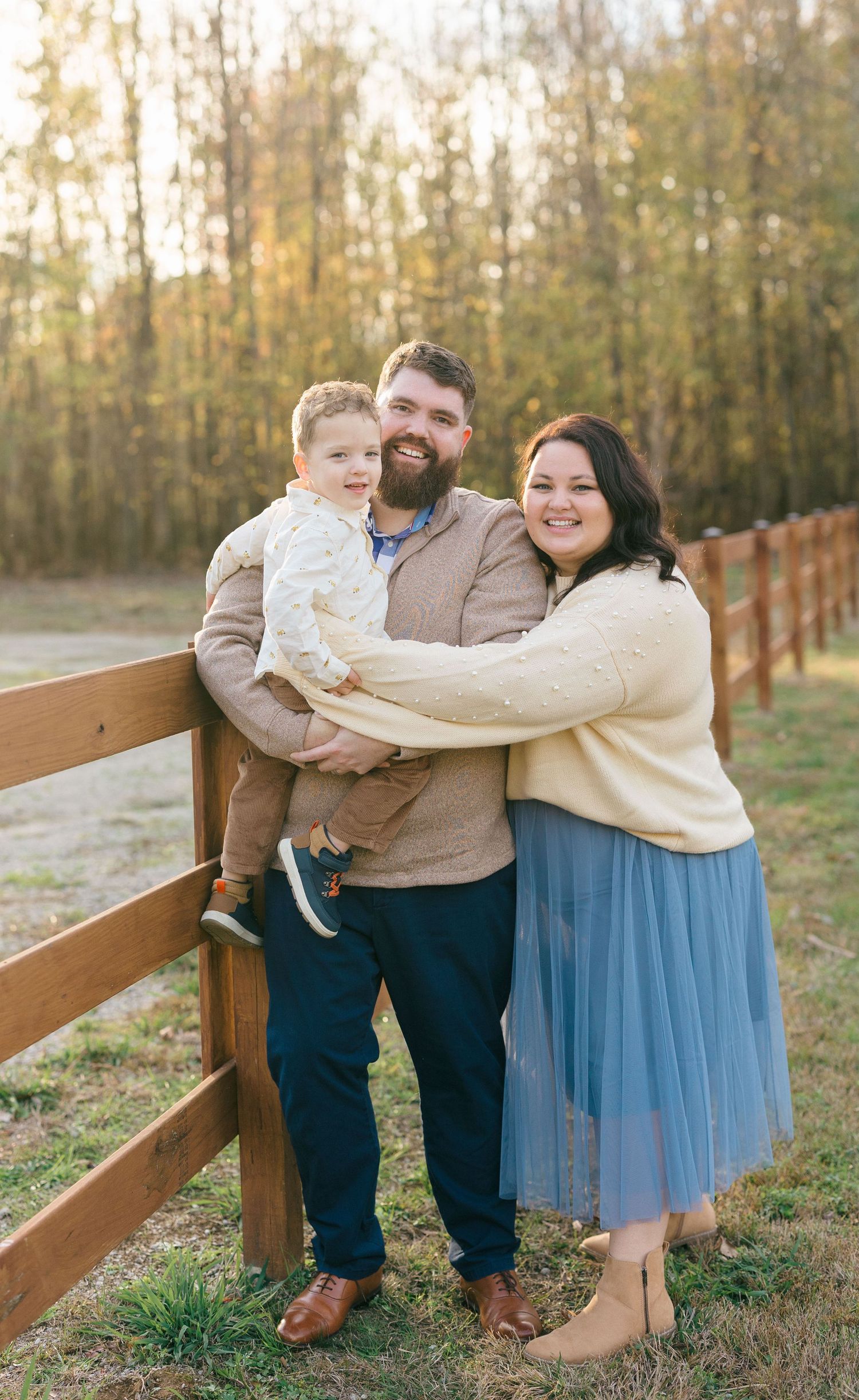 Family leaning on fence.