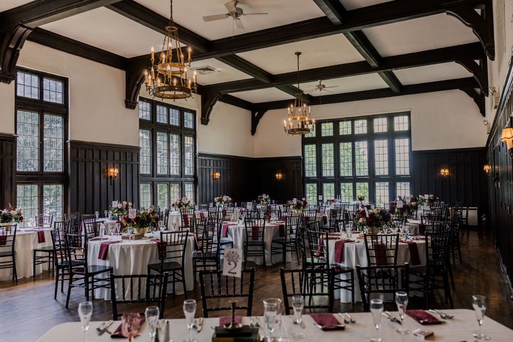 Grand ballroom with exposed beam ceiling and elegant table settings for wedding reception.