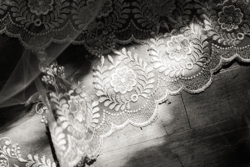 Artistic black and white detail shot of delicate wedding lace in natural light.