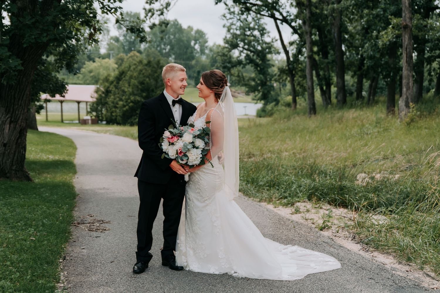A couple shares an intimate moment outdoors during their wedding photoshoot surrounded by lush greenery.