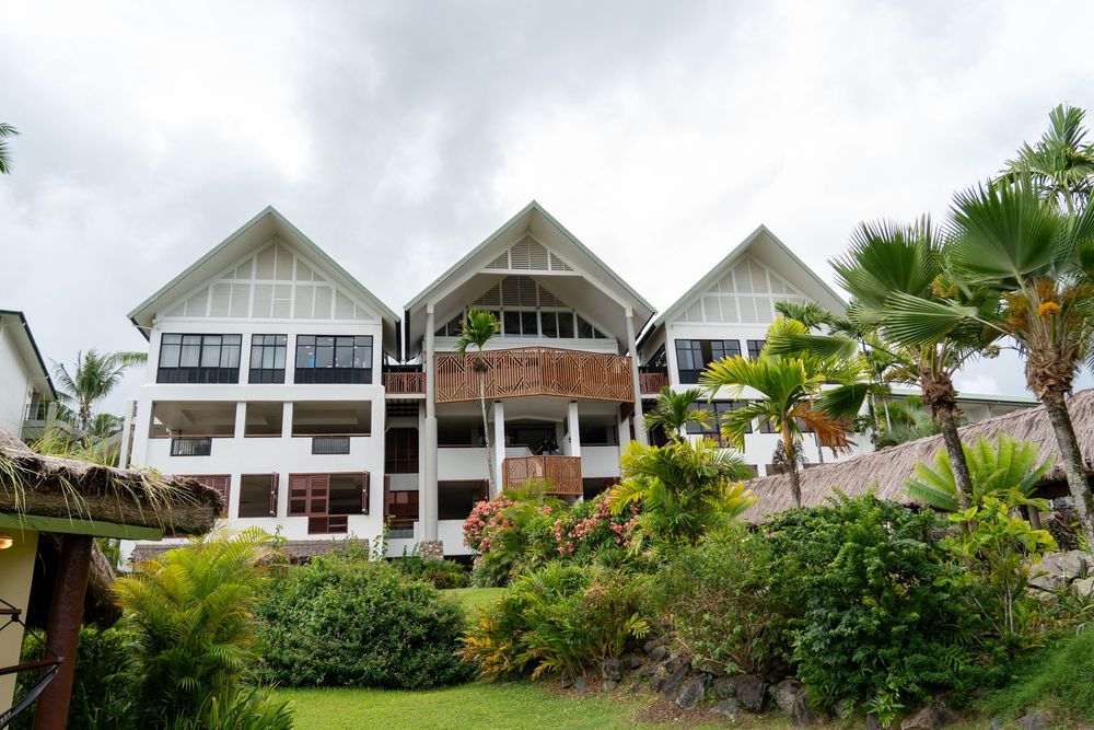 Modern white beach villas with tropical landscaping nestled on a hillside overlooking the ocean in a luxurious resort setting.