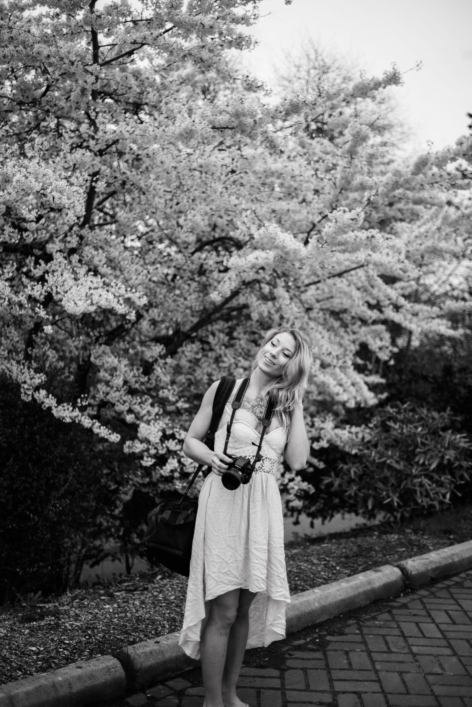 A joyful moment captured in black and white beneath blooming cherry trees.
