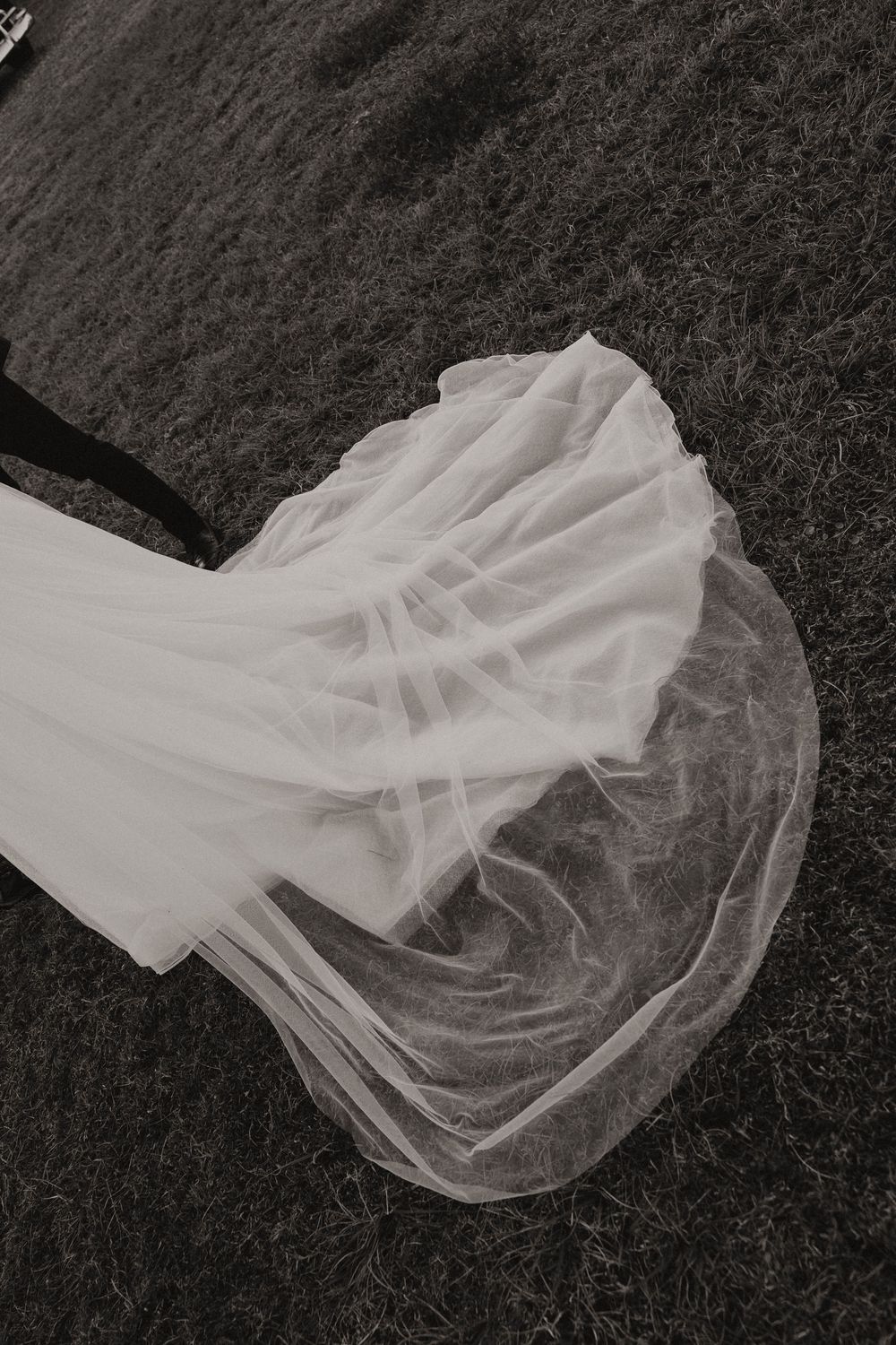 Sheer white tulle fabric draped in flowing patterns against a dark textured background.