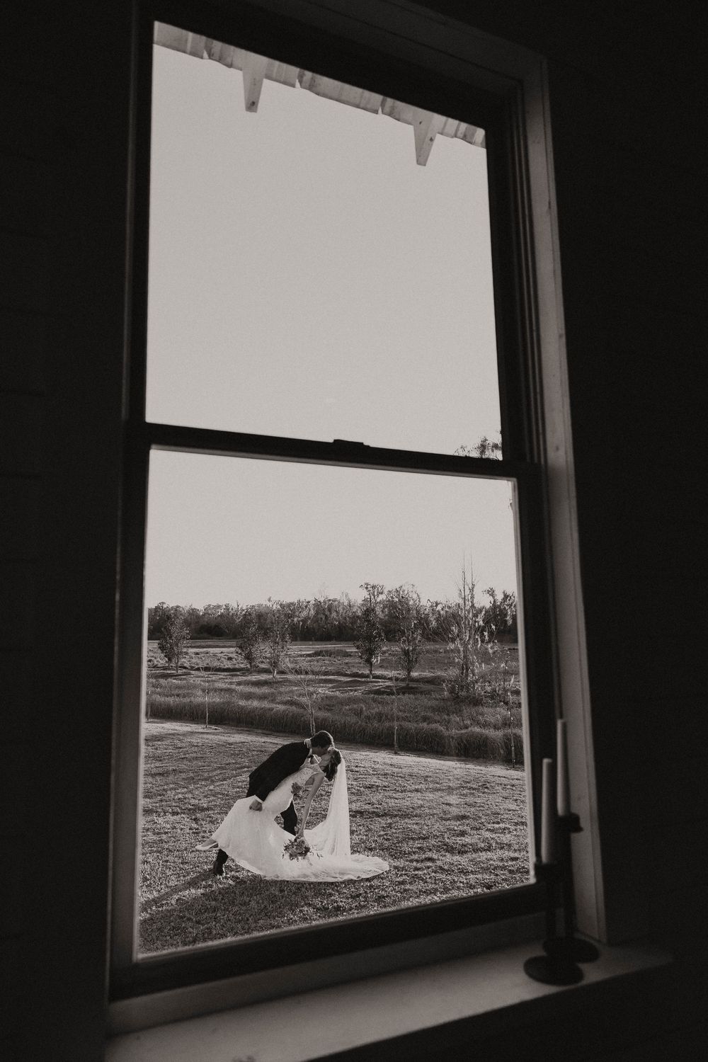 A triptych of black and white window views showing a rural landscape with fields and trees in the distance.