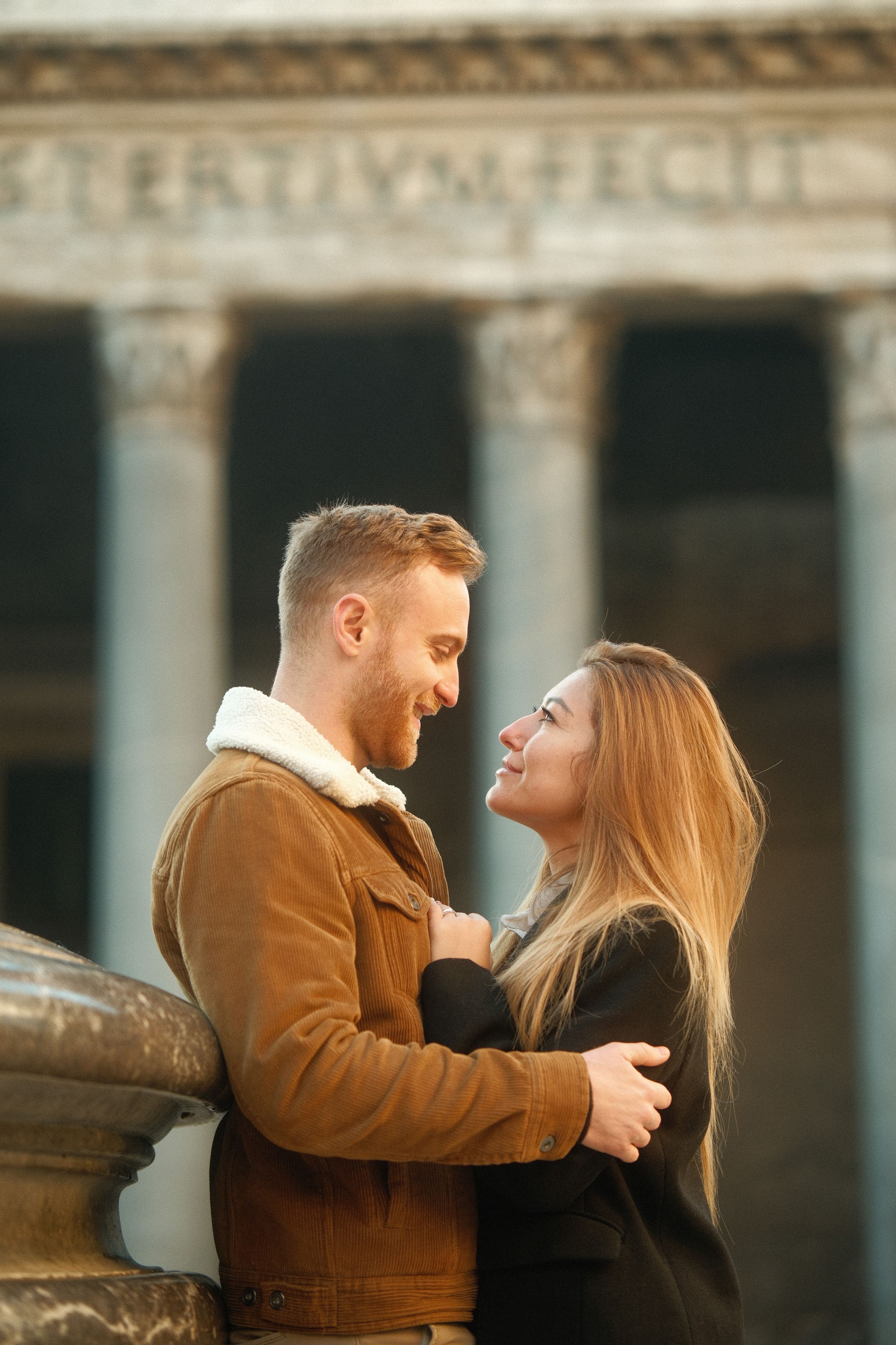 Romantic couple embracing near historic columns in Rome.