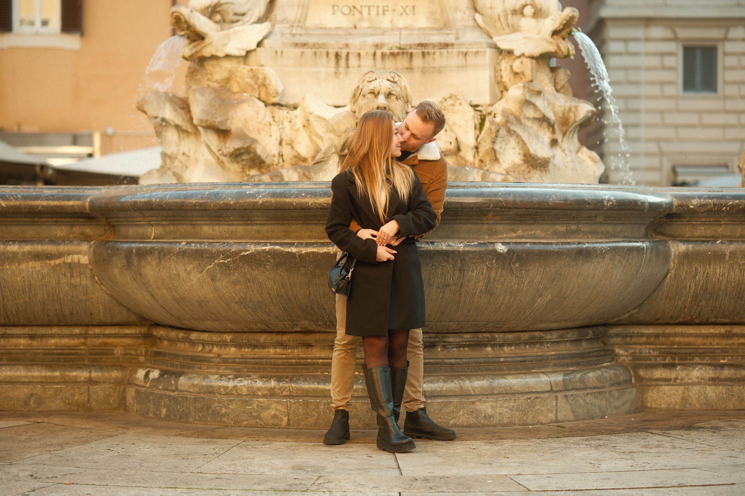 A romantic moment by an ornate stone fountain in Italy.