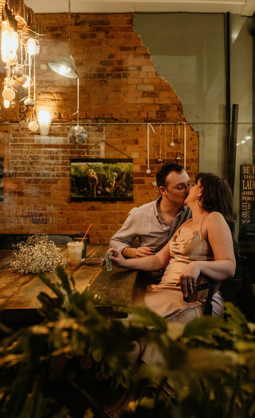 A couple shares an intimate moment in a rustic restaurant with exposed brick walls and ambient lighting.