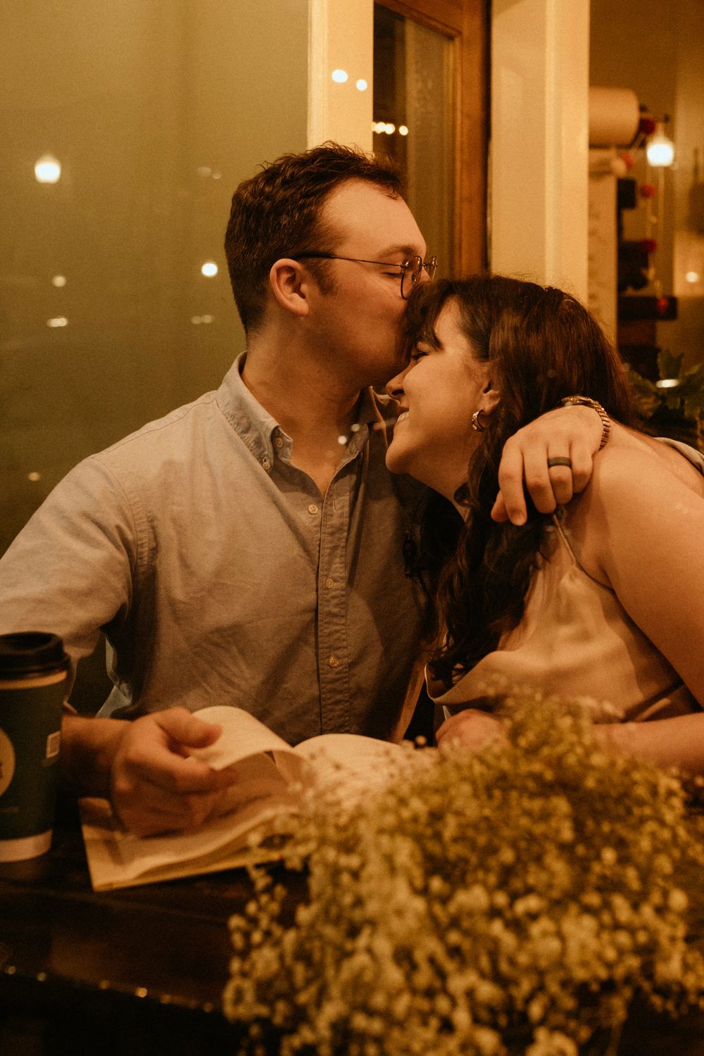 A warm, intimate moment between a couple at a cozy restaurant table with baby's breath flowers.