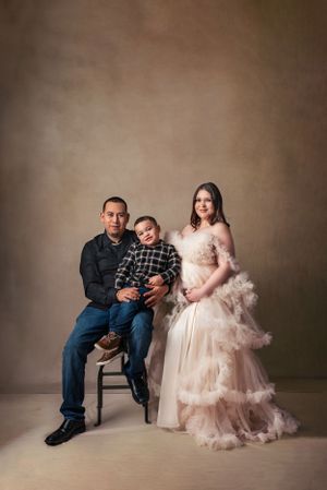 Studio portrait of family in formal attire against brown backdrop.
