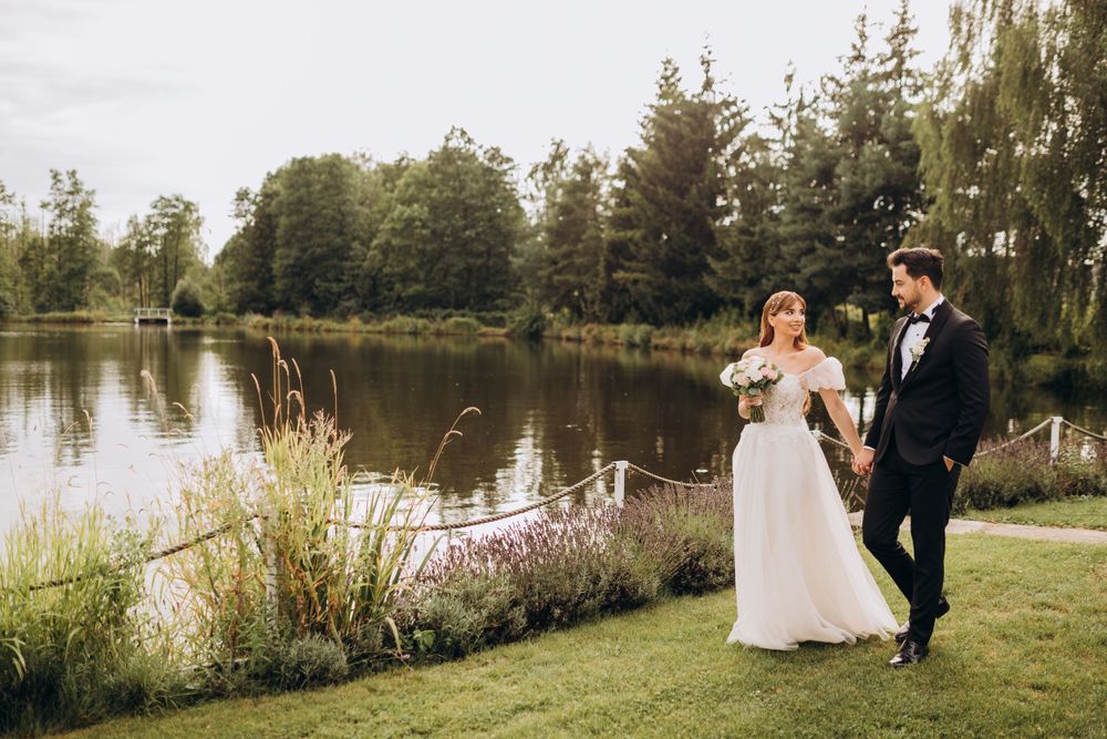A sunny lakeside wedding portrait with evergreen trees in the background.