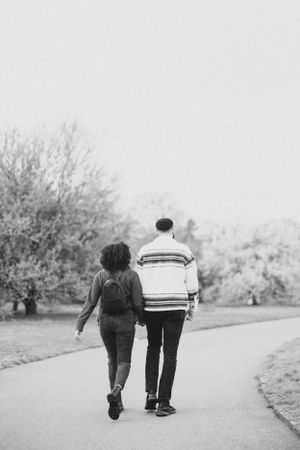 Black and white photo of a couple walking together on a garden path.