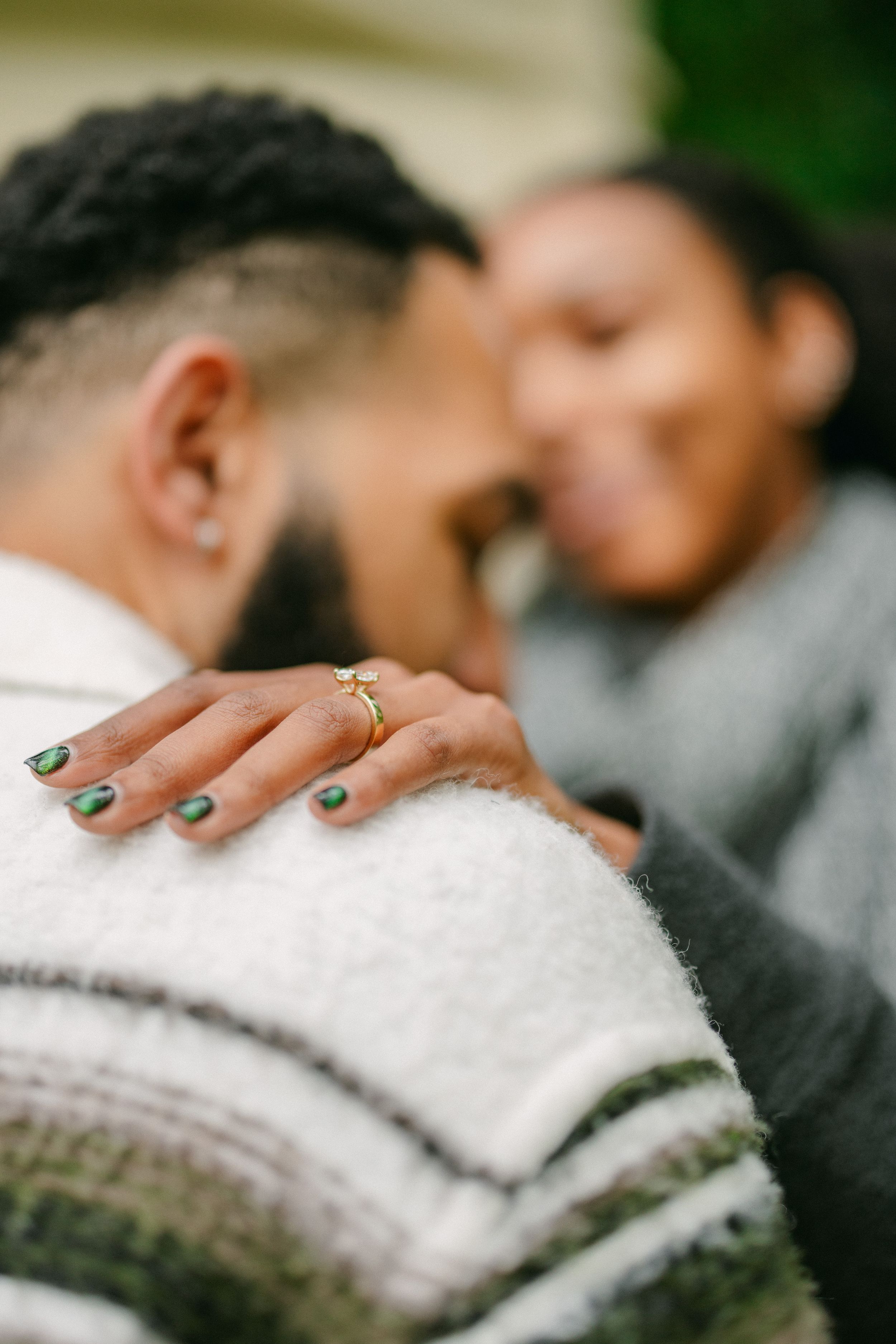 Close-up of hands with an engagement ring and green nail polish.