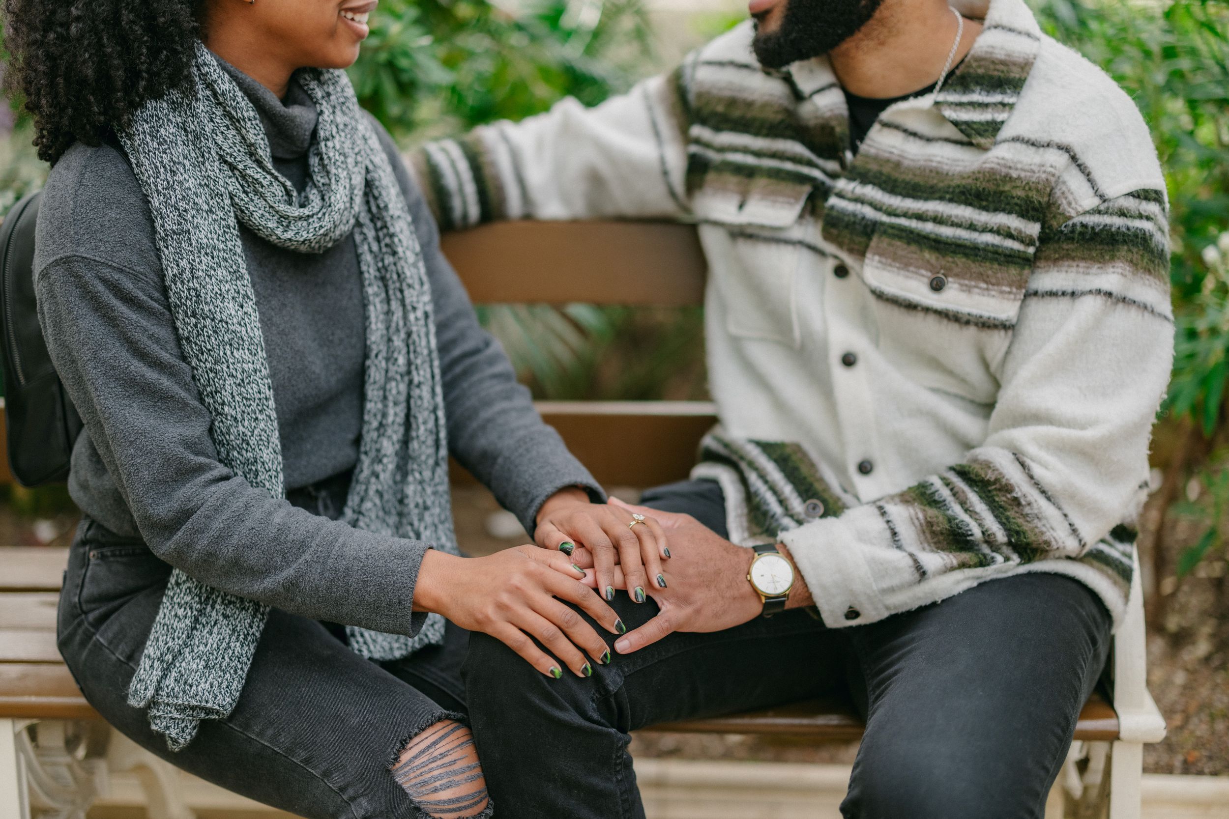 Two people sitting close together on a bench wearing warm winter clothing.