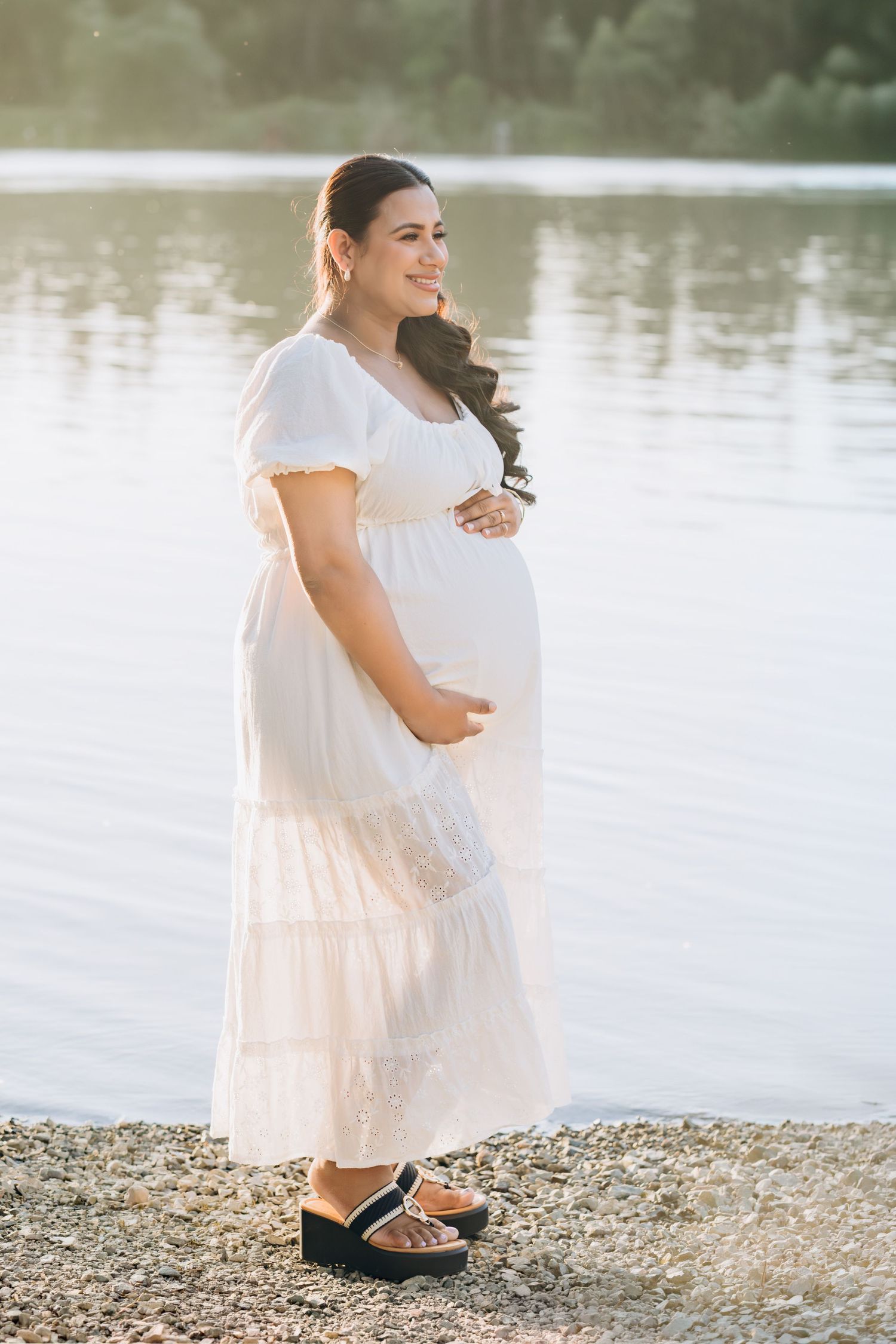 Couple in burgundy outfits share tender moment during maternity photoshoot.
