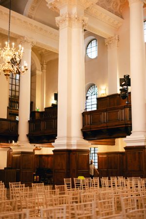 An elegant church interior with wooden pews, classical columns and a grand chandelier.