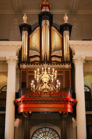 Grand pipe organ with ornate gold details and chandelier in historic venue.
