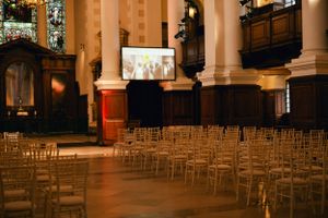 A church interior set up for an event with rows of chairs and a projection screen.