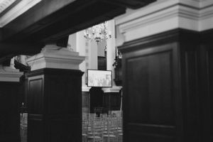 A black and white view of wooden church pews and architectural details.