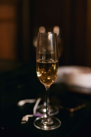 A champagne flute filled with sparkling wine against a dark moody background.