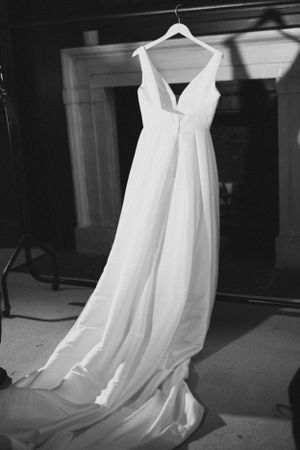 Elegant white wedding dress hanging on display with flowing train.