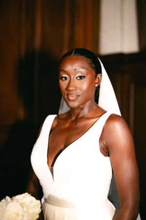 A radiant bride poses in an elegant white V-neck wedding gown with a flowing veil.