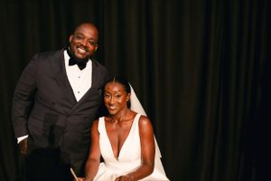 Formal wedding portrait against dark backdrop showing elegant attire.