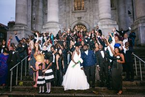 Wedding guests celebrate on grand stone steps of historic building during evening reception.