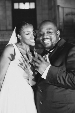 Candid black and white portrait of newlyweds showing off ring after ceremony.
