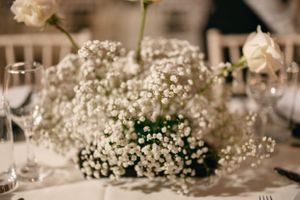Delicate baby's breath and white rose floral centerpiece arrangement on an elegant table setting.