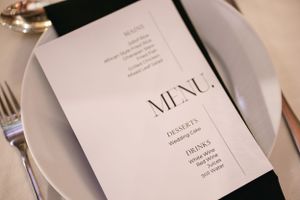 Closeup of a minimalist black and white wedding menu card on a formal place setting.