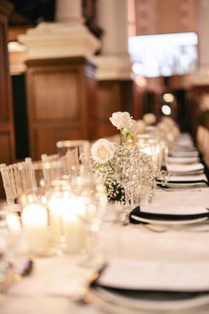 Elegant table setting with white flowers, candles and place settings for a formal event.
