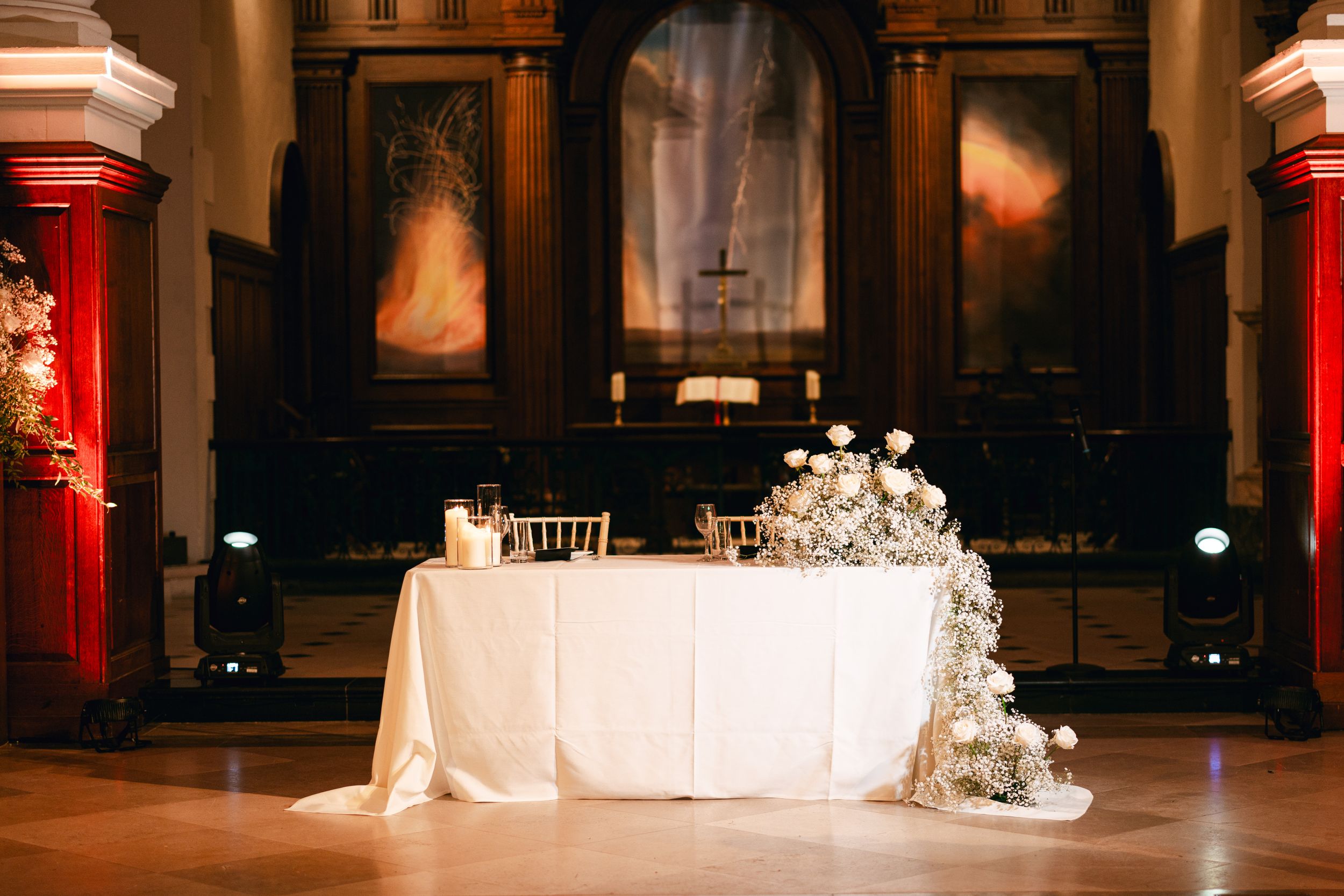 Elegant white wedding reception table with floral decorations in a grand church venue.