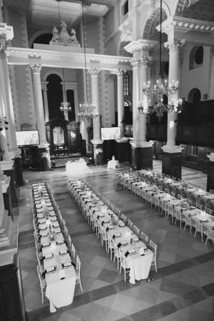 Black and white photo of an ornate church interior set up for a wedding reception with rows of tables.