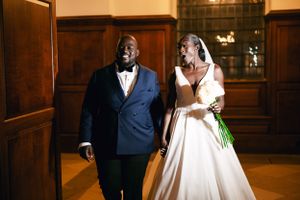 A couple in wedding attire sharing a joyful moment in a wood-paneled hallway.