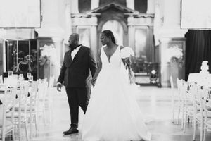 Black and white photo of a couple walking down church aisle in wedding attire.