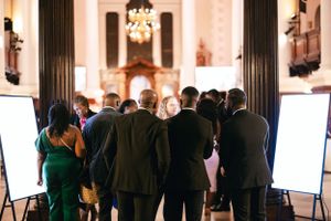 Wedding guests gathered around display boards at an elegant venue.