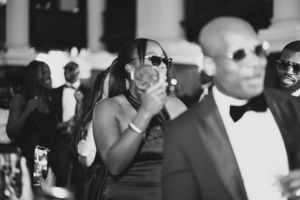 Black and white photo of wedding guests dancing and celebrating at an elegant reception.