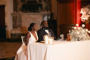 Newlyweds sitting at their sweetheart table with candlelight and floral decorations.