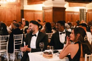 Elegant wedding reception with guests in formal attire seated at decorated tables.