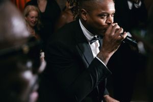 Person in tuxedo performing with microphone at formal event.