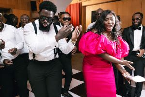 Wedding guests dancing and celebrating in formal attire at reception party.