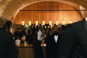 Elegant arched bar area with hanging lights and formal guests mingling.
